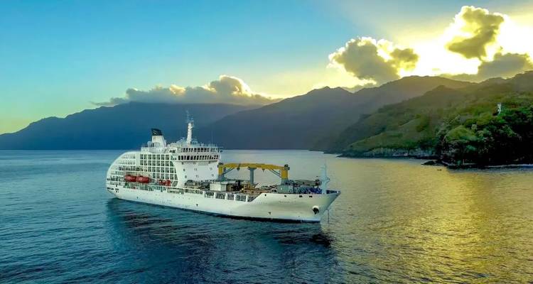 Kreuzfahrtschiff segelt bei Sonnenaufgang an dunklen Bergen vorbei, goldenes Licht bricht durch die Wolken.