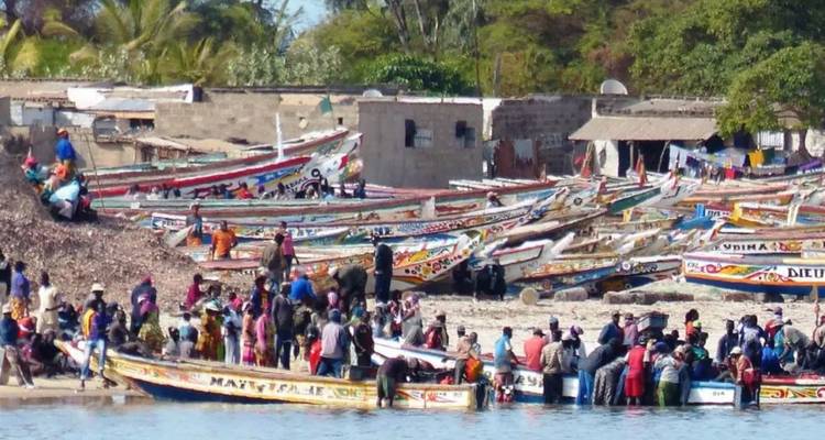 Rivage animé bondé de pirogues de pêche peintes et de foule grouillante