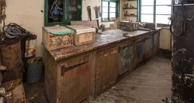 Old wooden workbench and tools inside a weather-beaten Antarctic outpost hut.