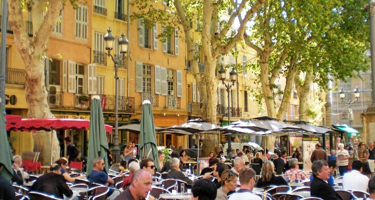 Scène animée de café en plein air sous des platanes le long d'une avenue provençale ensoleillée