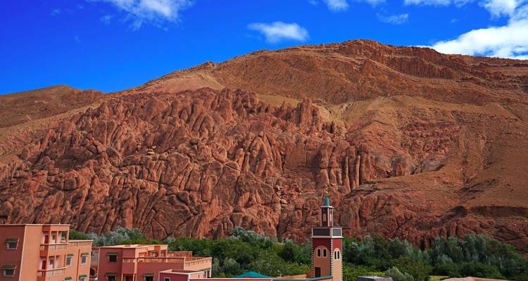 Red rocky hills with a mosque tower and buildings below.