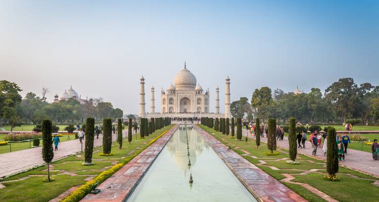 The Taj Mahal with tourists walking in the foreground garden.