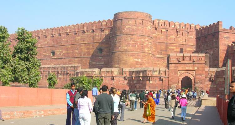Visitors walking towards the red sandstone walls of a historic fort.