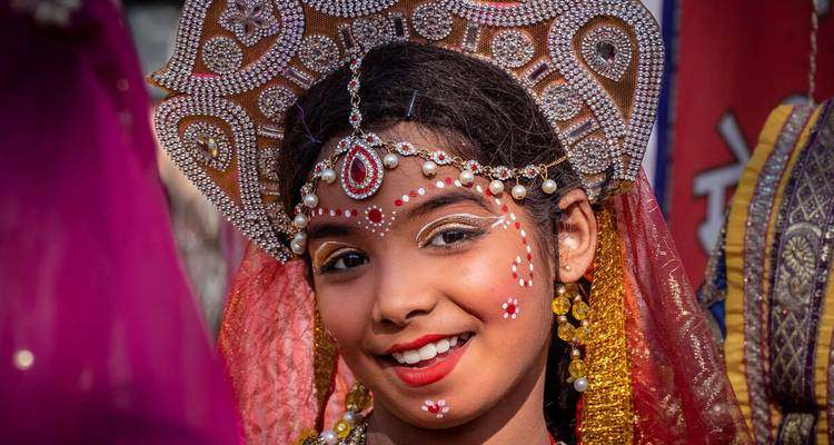 Ein junges Mädchen in traditioneller indischer Kleidung und Kopfbedeckung, das lächelt.