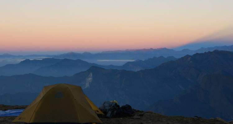 Vue du coucher de soleil sur les montagnes avec un camping de tentes.