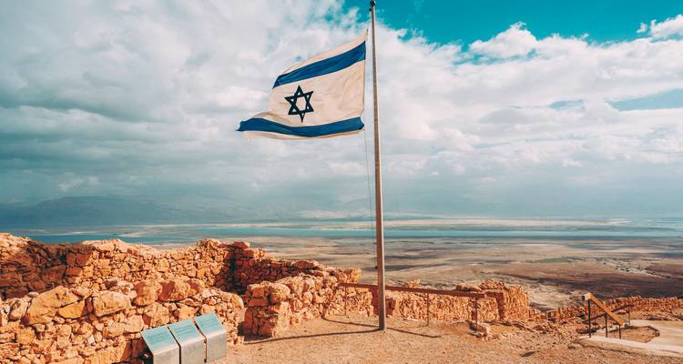 Israelische Flagge weht hoch über historischen Ruinen mit weiten Landschaften im Hintergrund.