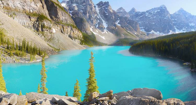 Lac alimenté par un glacier turquoise encadré par des pics enneigés escarpés et une forêt de pins.