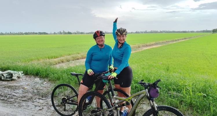 Two women with bicycles in a green field.