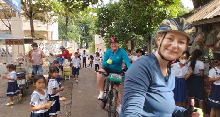 Cyclists interacting with children in a rural street.