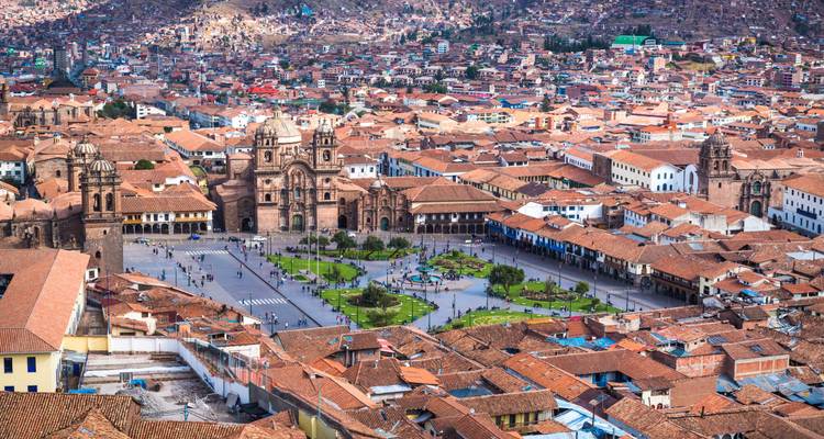 Vue aérienne expansive de la Plaza de Armas de Cusco avec les tours jumelles de la cathédrale entourées de toits en terre cuite.