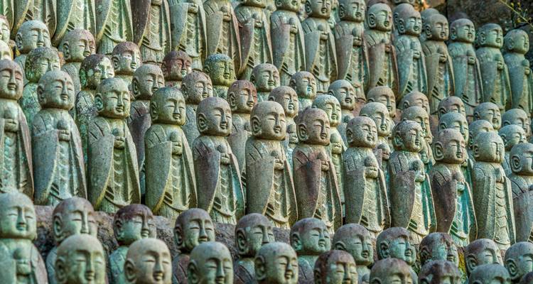 Filas de pequeñas estatuas de piedra de Jizo se alinean en un patrón contemplativo en un templo japonés.