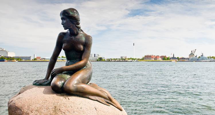 Estatua de bronce de la Sirenita sentada en una roca junto al puerto de Copenhague.