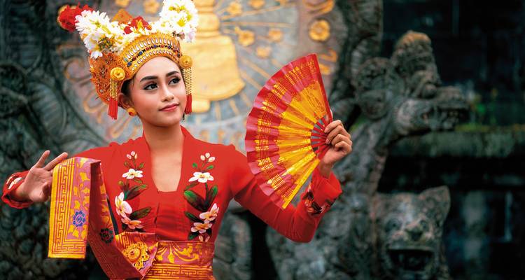 Balinese woman in traditional attire performing a dance.