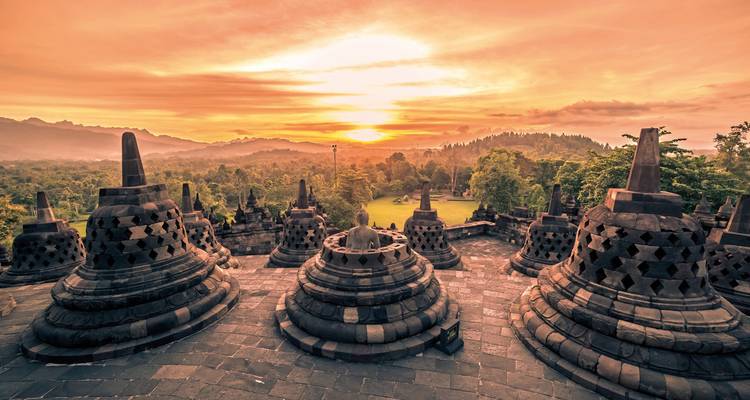 Sunset view of Borobudur temple with stupas in the foreground.
