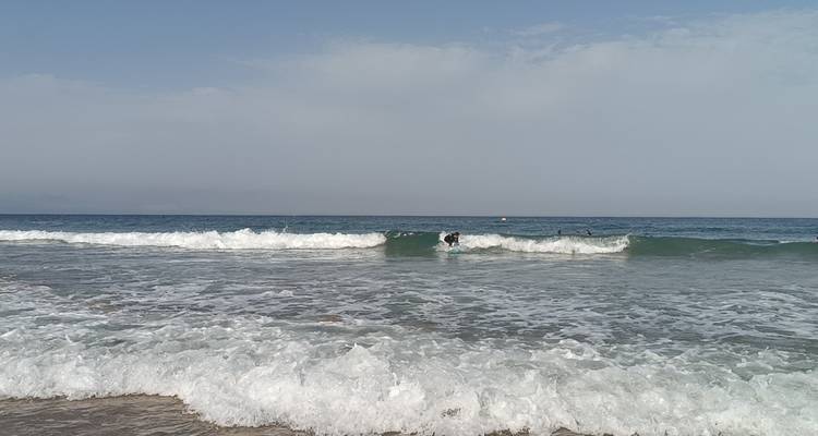 Vagues se brisant sur une plage avec un ciel nuageux.