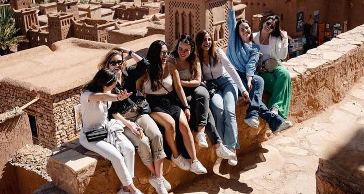 Gruppe von Menschen, die auf einer Mauer in einem historischen Bereich sitzen.