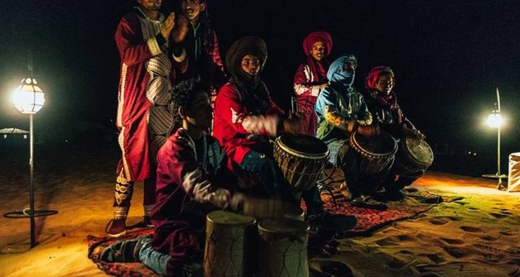 Gruppe von Musikern, die nachts in einer Wüstenumgebung auftreten.