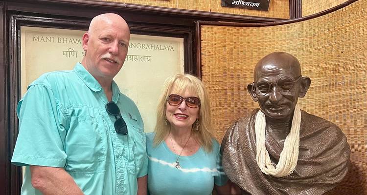 Couple posing with a statue of Mahatma Gandhi at a museum.