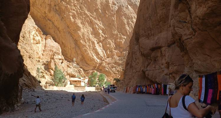 Des gens explorant une gorge rocheuse avec des marchandises colorées exposées.