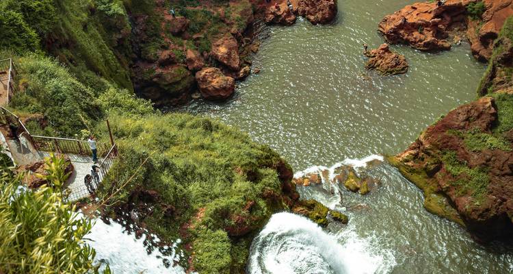 Ein erhöhter Aussichtspunkt offenbart üppige Klippen und stürzendes Wasser, das in ein grünes Becken unter Marokkos Ouzoud-Wasserfällen stürzt.
