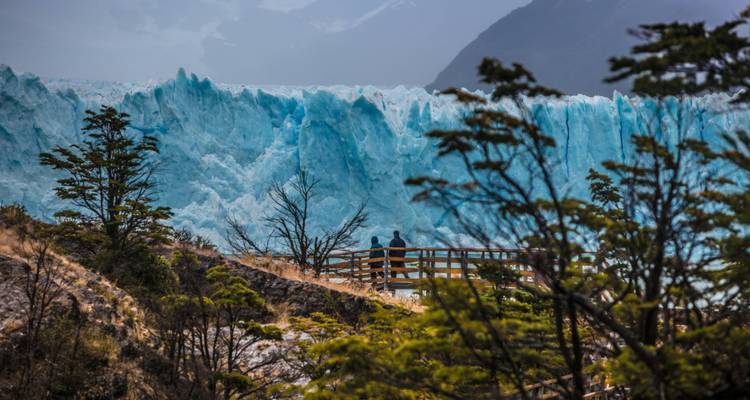 Besucher, die einen massiven Gletscher aus der Ferne beobachten.