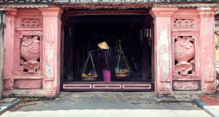 Un mercado tradicional con un vendedor cargando un yugo de canastas.