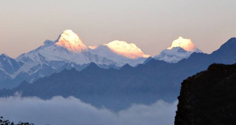 Sunset over distant mountain peaks with some peaks illuminated in golden light.
