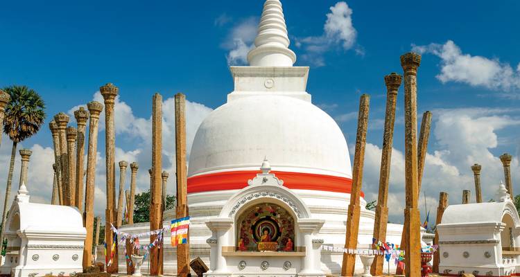 Weiße Stupas mit bunten Fahnen an einer heiligen Stätte.