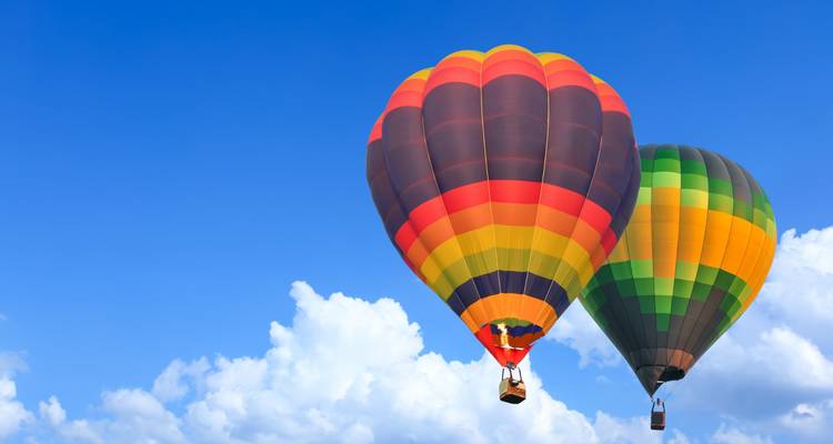 Deux montgolfières flottant dans un ciel lumineux avec des nuages.