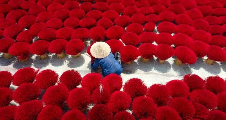 Person arranging red incense sticks in a pattern.