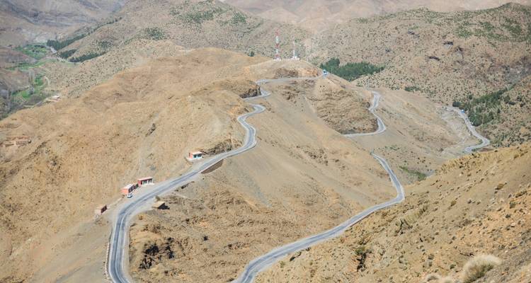 Kurvenreiche Straße durch eine karge, felsige Berglandschaft.