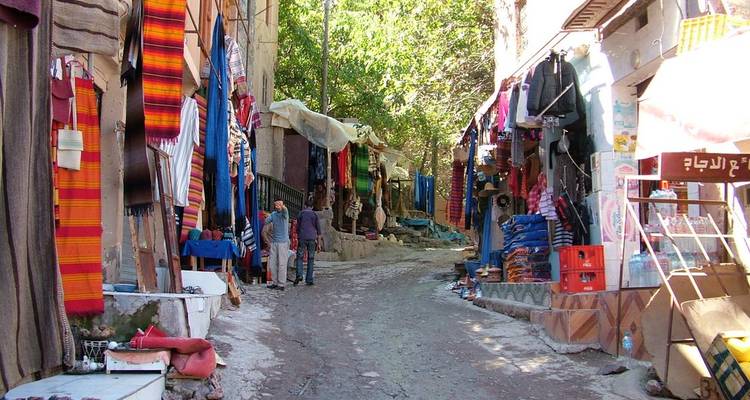 Een smalle straat met kleurrijke textiel en lokale marktkraampjes.