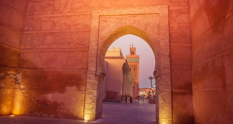 Une porte historique avec une vue sur une tour dans la lumière du soir.