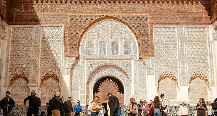 Cour de la Médersa Ben Youssef avec un carrelage islamique orné grouillant de touristes.