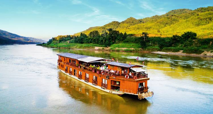 Cruise boat on a river surrounded by hills and forests.