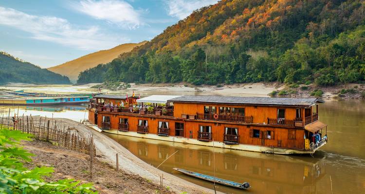 Cruise boat docked along the riverbank with surrounding forests.