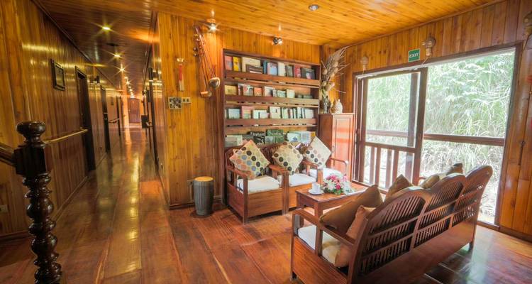 Interior of a wooden boat with seating area and bookshelf.