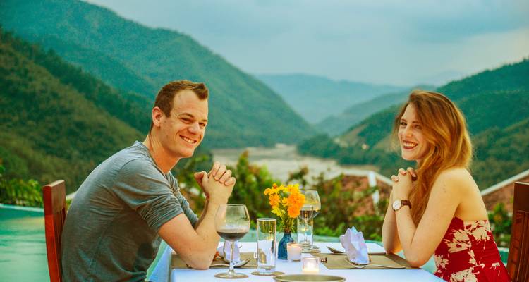 Couple dining outdoors with a beautiful mountain and river view.