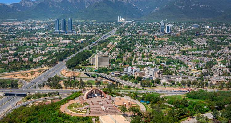 Stadsgezicht met hoofdwegen en een moskee met bergen op de achtergrond.