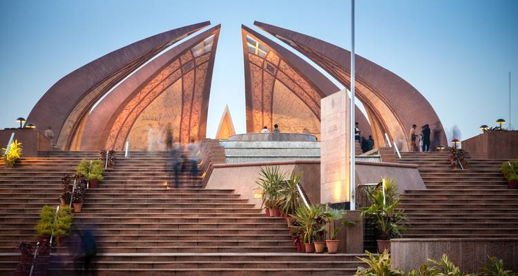Monument met grote bloembladvormige structuren en mensen op de trap.
