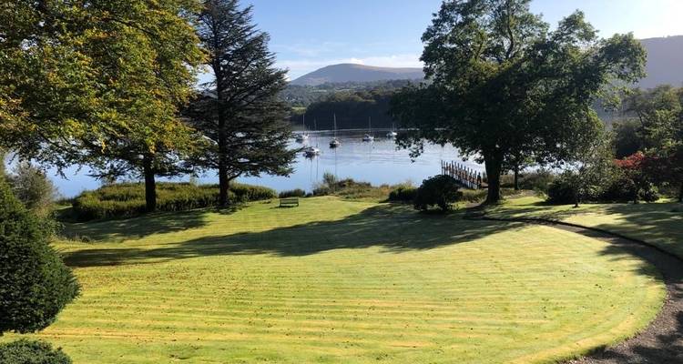 Lush garden with a view of a lake and distant hills.