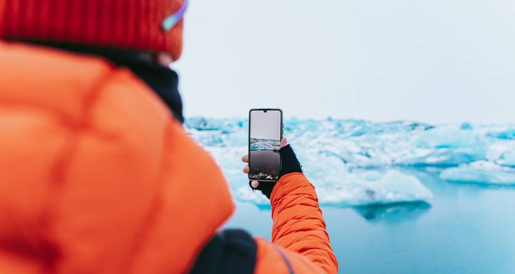 Persona tomando una foto de icebergs con un teléfono inteligente.