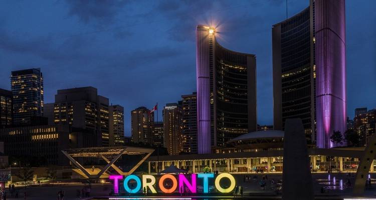 Toronto city view with illuminated City Hall and colorful sign at night.
