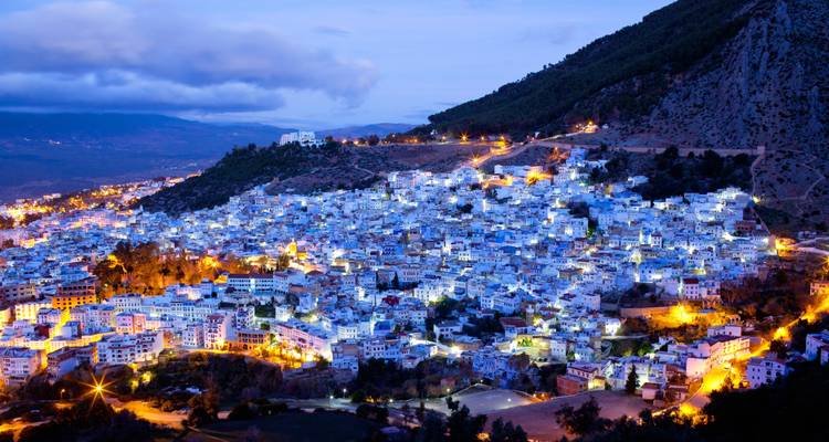 Vista nocturna de una ciudad con edificios blancos y azules iluminados.