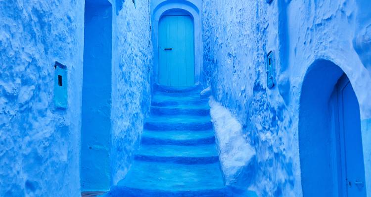 Escalier bleu et portes dans une ruelle lumineuse.