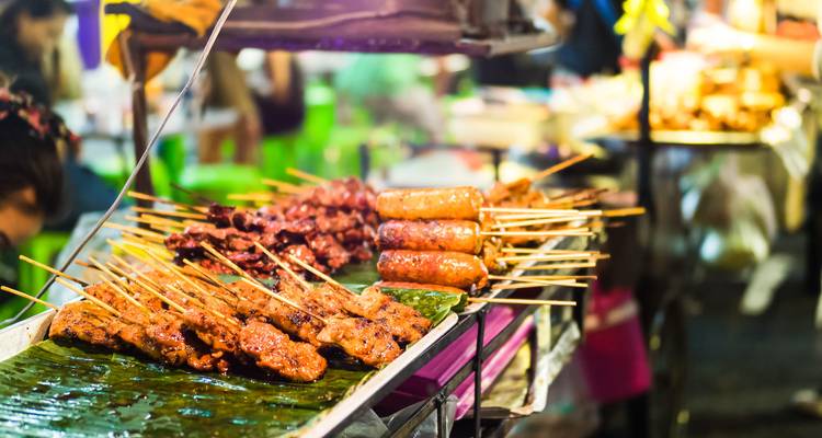 Straßenimbissstand mit Spießen auf einem Markt.