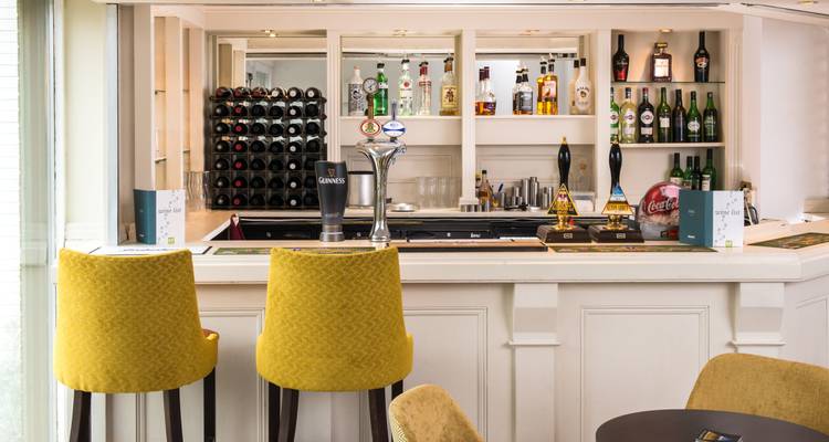 Ein Barbereich im Innenraum mit ausgestellten Flaschen und Zapfhähnen.
