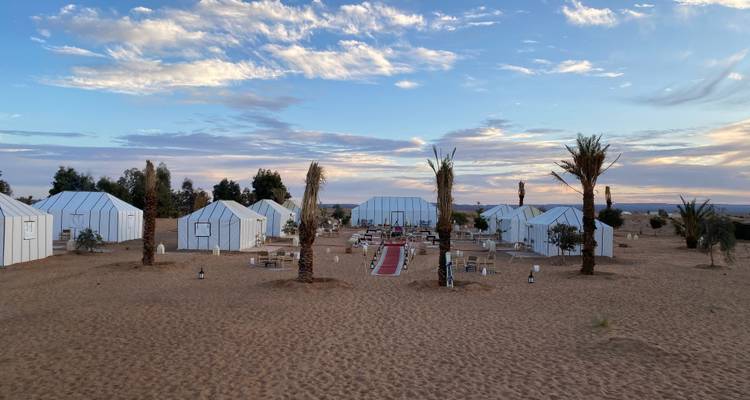 Desert camp with rows of tents under a blue sky.