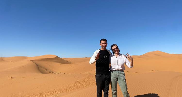 Two people posing on the sand dunes in the desert.