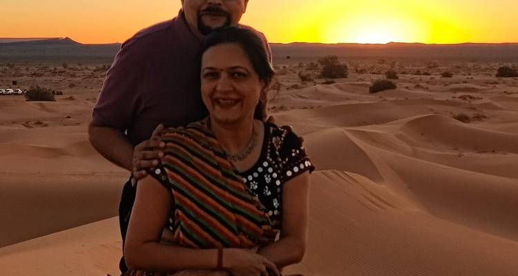 Couple posing on sand dunes during sunset.